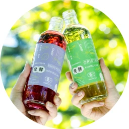 木漏れ日の中で 2 本のドリンクボトルを掲げる手